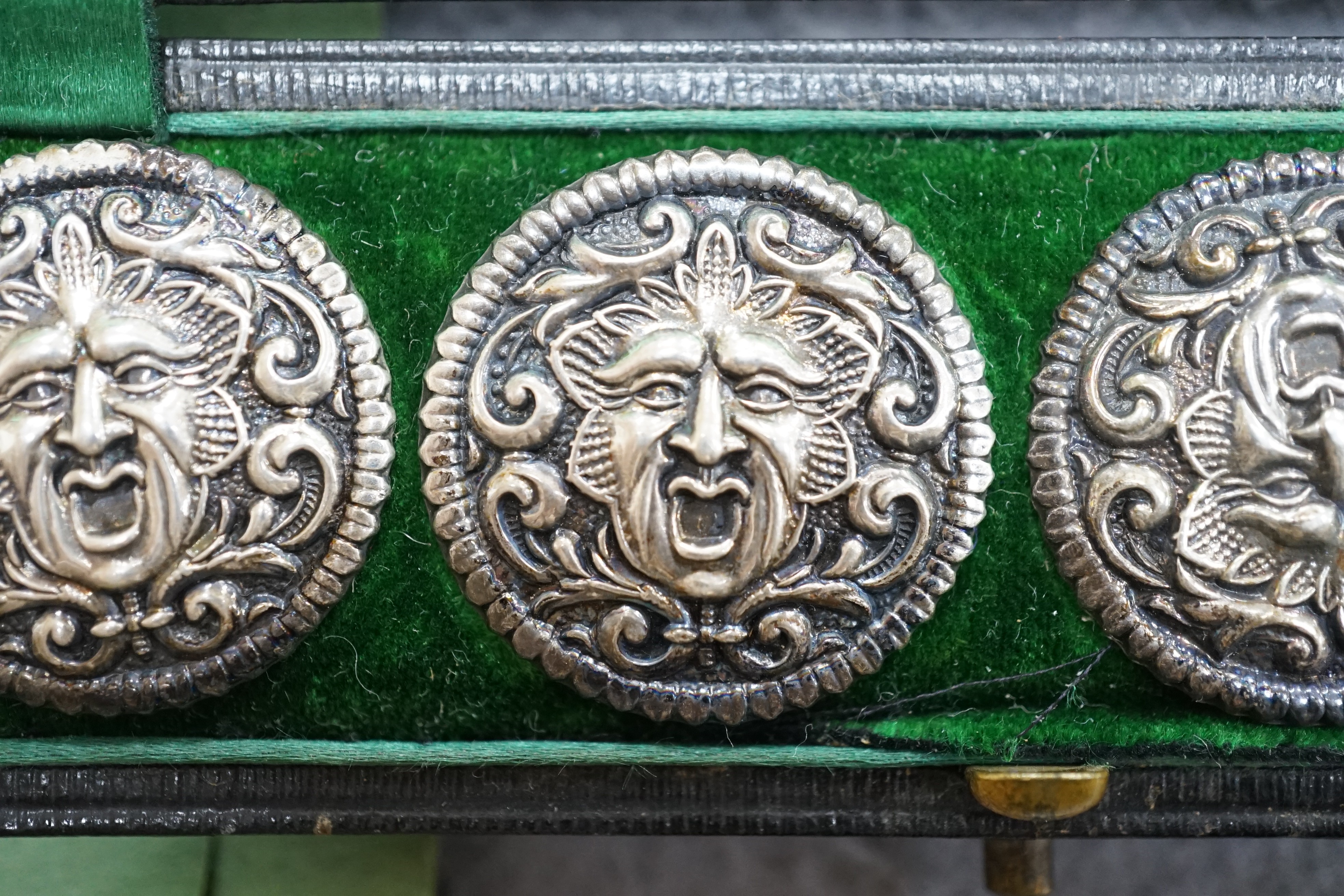 A cased set of six Edwardian silver buttons, each embossed with a mask, Henry Matthews, Birmingham, 1902, 27mm.